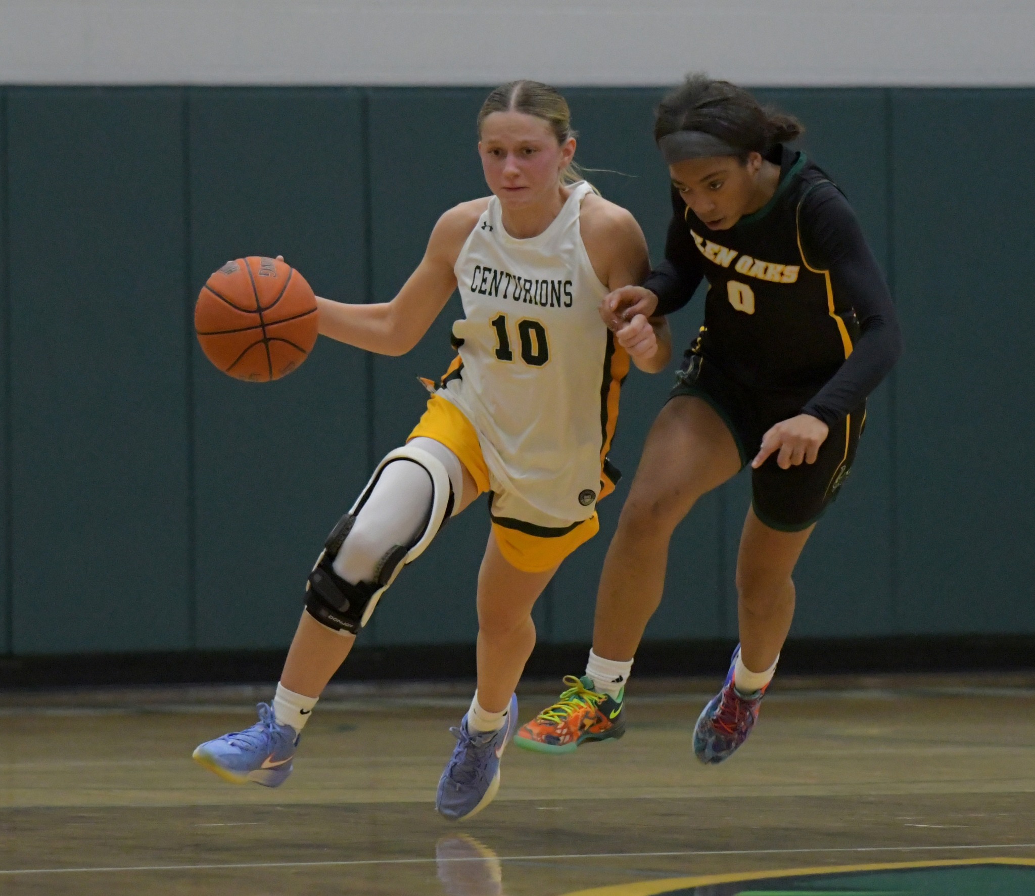 MCC Women's Basketball player dribbling and defending the ball against a Glen Oaks player.