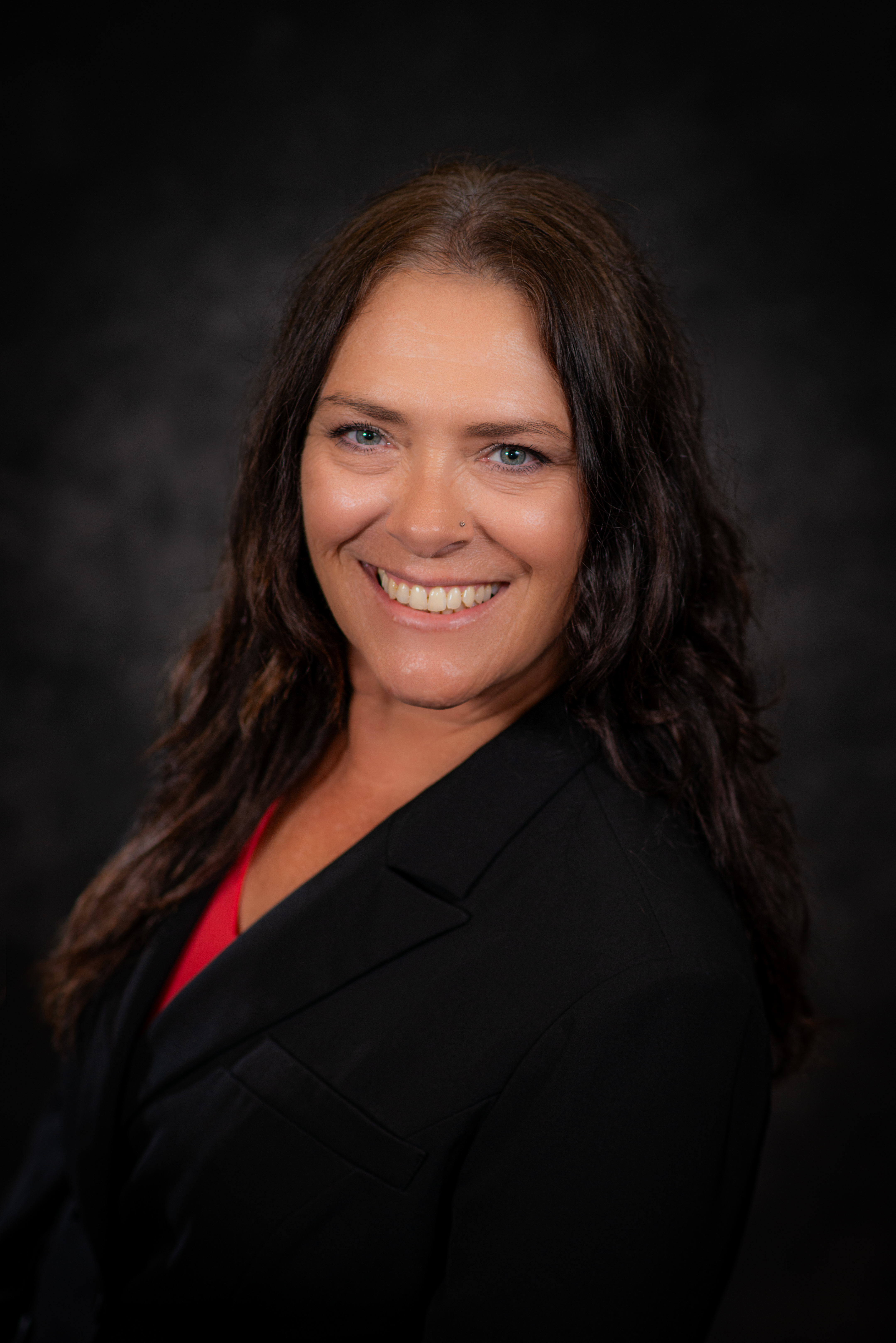 Professional photo of Angie Williams weraing a black blazer and red shirt smiling at the camera.