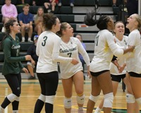 MCC women's volleyball team celebrates on the court during a match.