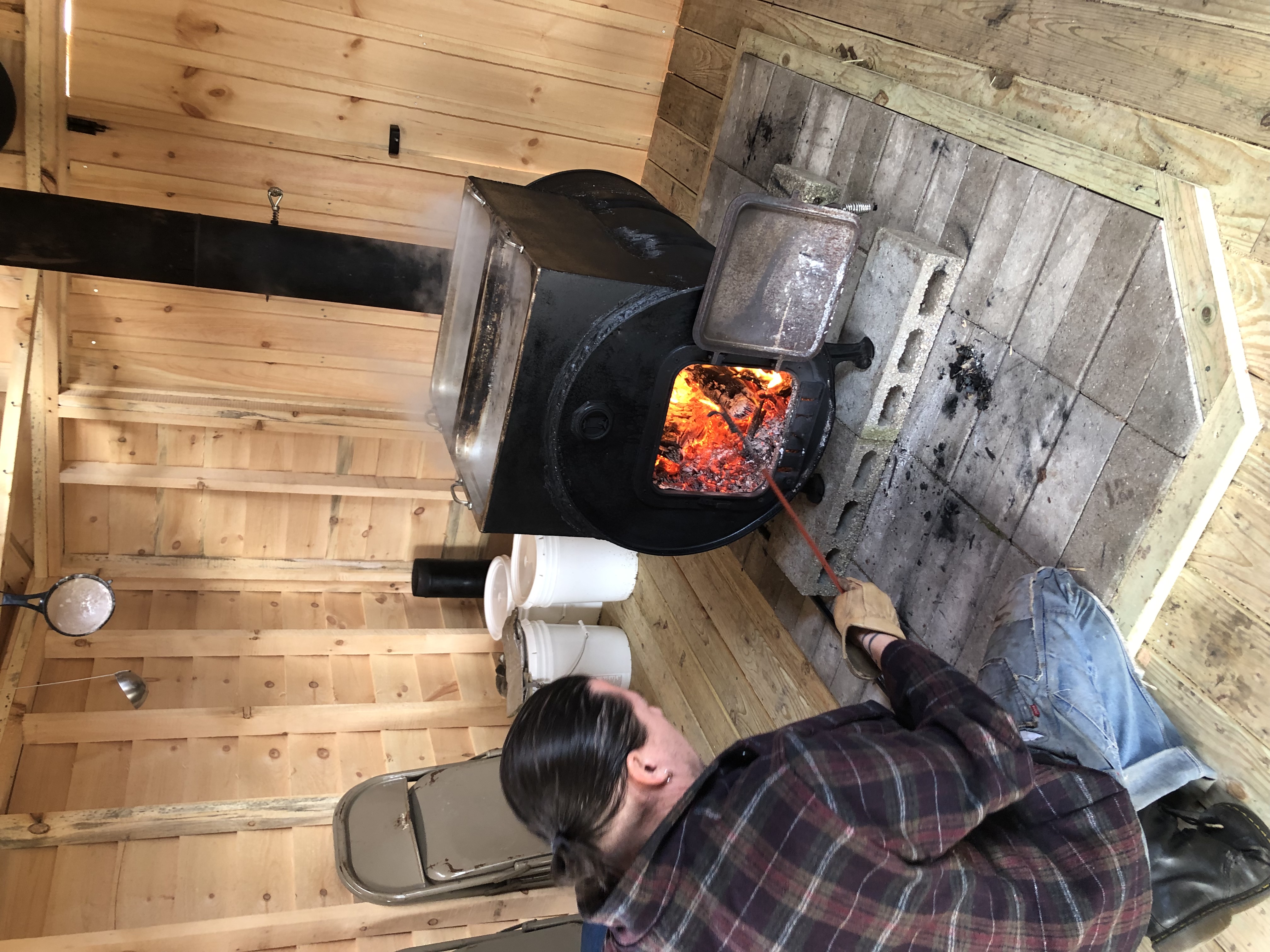 Instructor Seth Sutton stoking the woodstove fire in the Sugar Shack