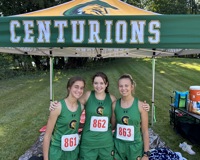 A group of three MCC women's cross country athlete pose for a photo in front of their team tent.