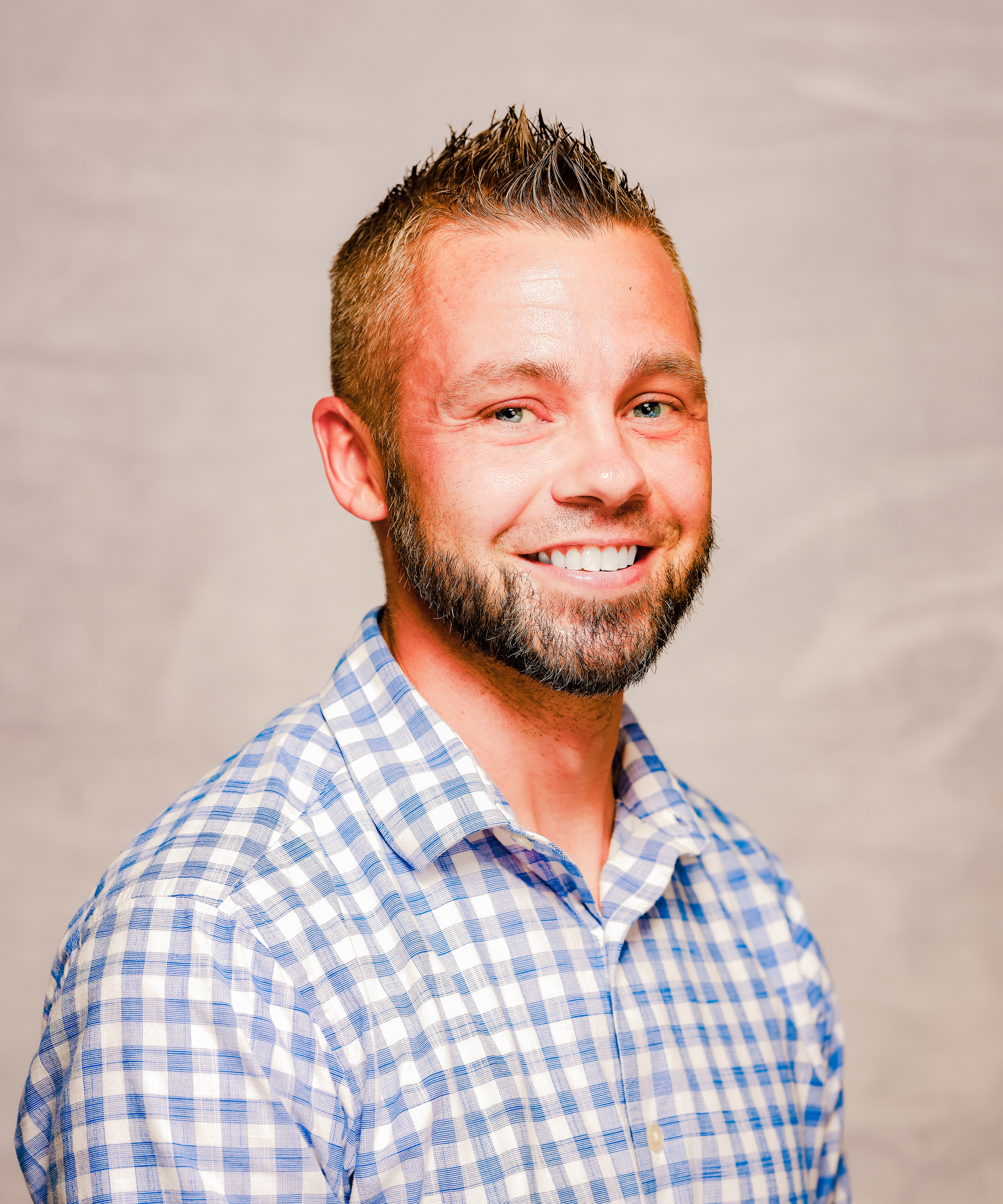 Headshot of Bob Byram smiling and wearing a blue and white checked shirt.