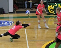 MCC volleyball player dives to bump an incoming ball on the court.